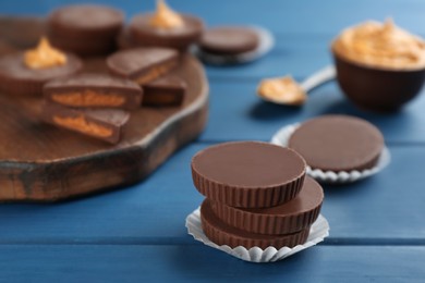 Delicious peanut butter cups on blue wooden table, space for text