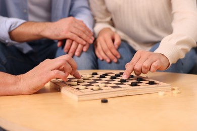Photo of People playing checkers at wooden table, closeup
