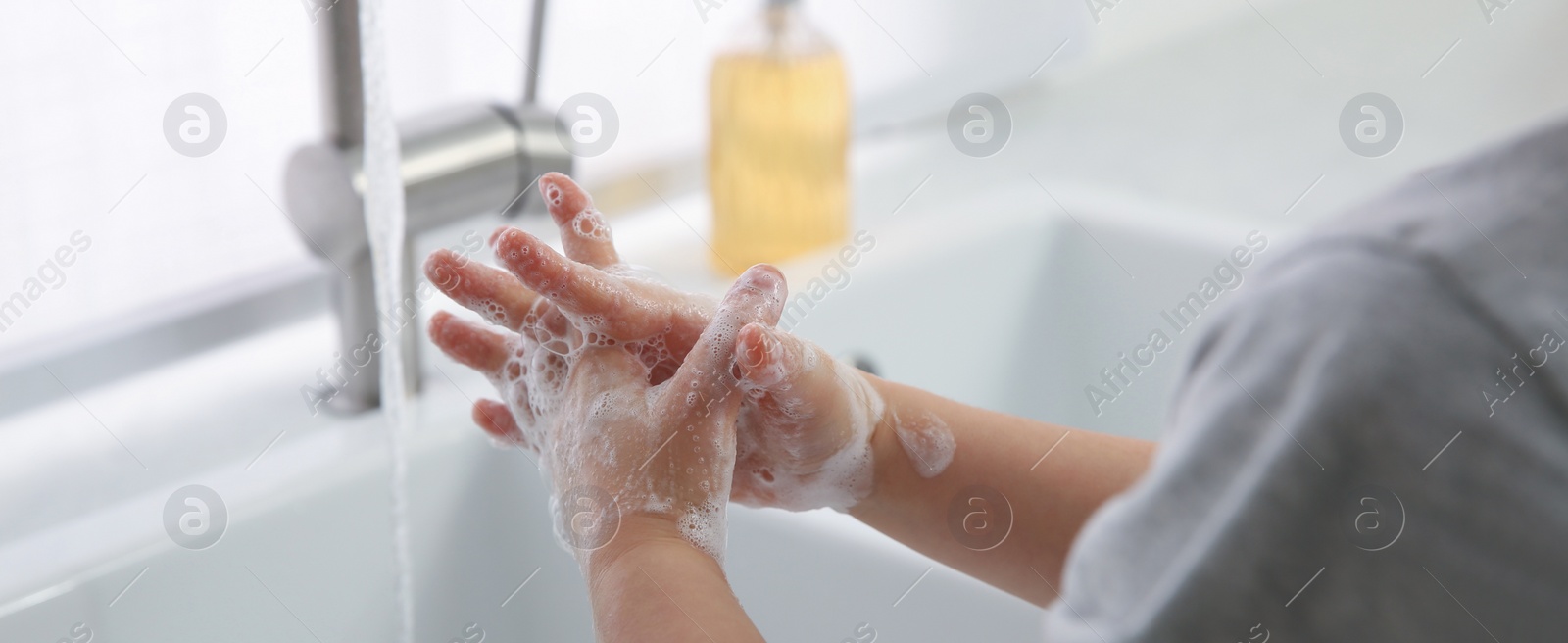 Image of Boy washing hands with liquid soap over sink, closeup. Banner design