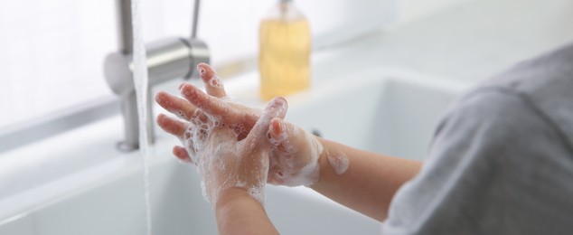 Image of Boy washing hands with liquid soap over sink, closeup. Banner design