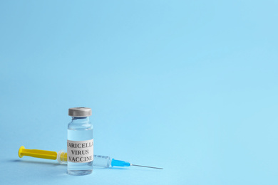 Photo of Chickenpox vaccine and syringe on light blue background, space for text. Varicella virus prevention