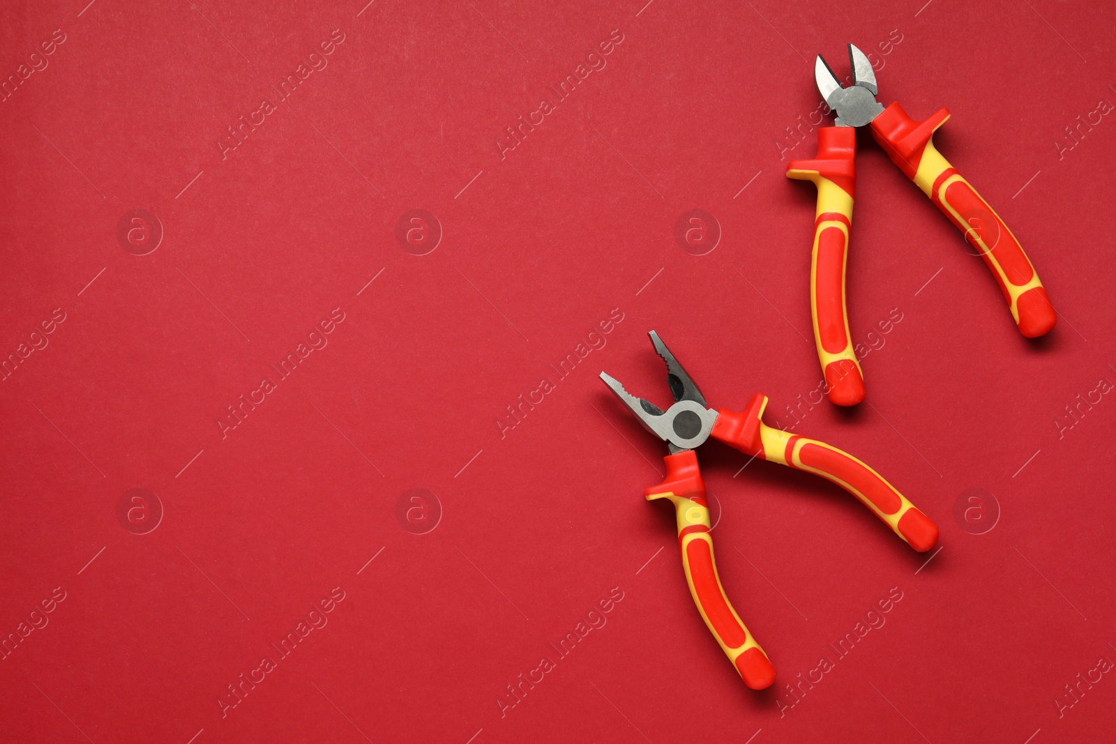 Photo of Pliers on red background, flat lay. Space for text
