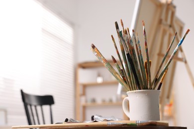 Photo of Different paintbrushes in studio with drawing eassel. Artist's workplace