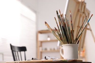 Different paintbrushes in studio with drawing eassel. Artist's workplace