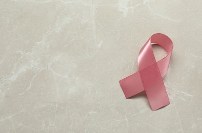 Breast cancer awareness. Pink ribbon on light grey table, top view. Space for text