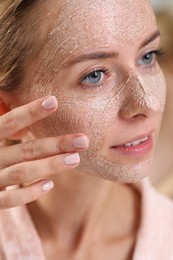 Photo of Woman applying face mask on blurred background, closeup. Spa treatments