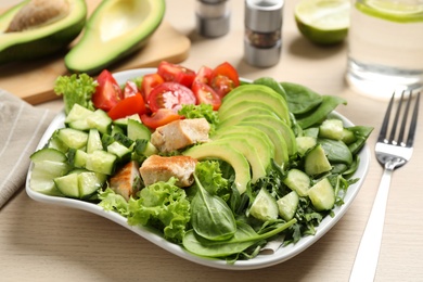 Delicious avocado salad with fried chicken on wooden table