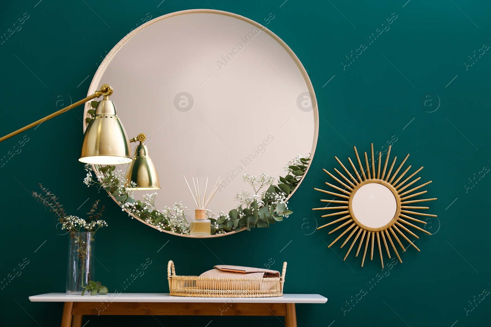 Photo of Round mirror and table with accessories near green wall in modern room interior