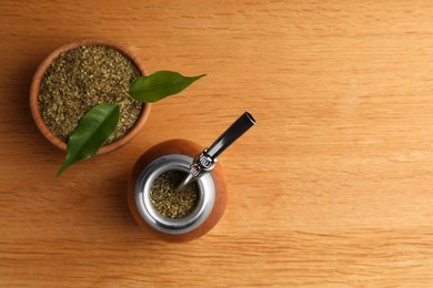 Photo of Calabash with mate tea and bombilla on wooden table, flat lay. Space for text