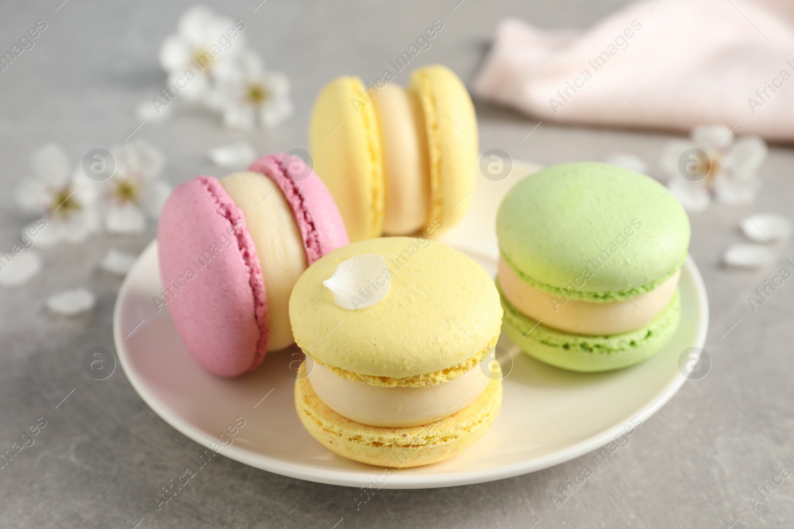 Photo of Delicious colorful macarons on grey table, closeup