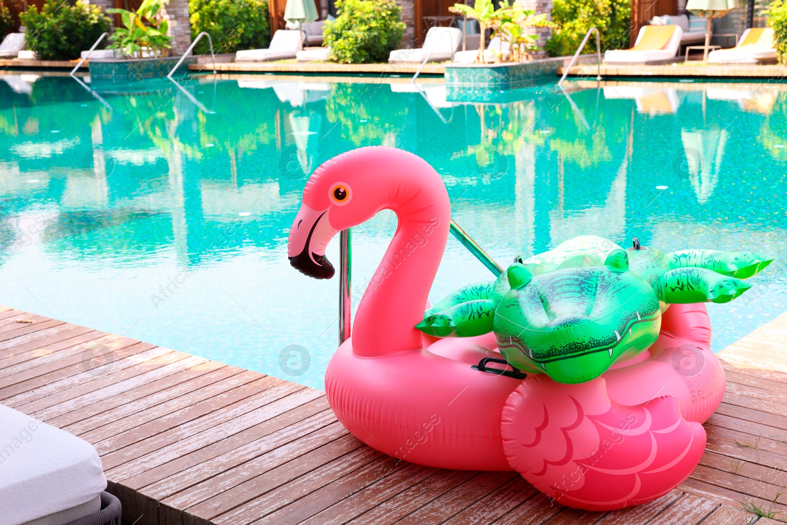 Photo of Floats in shape of crocodile and flamingo on wooden deck near swimming pool at luxury resort