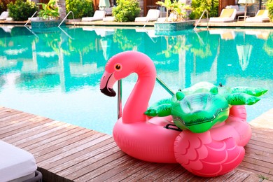 Photo of Floats in shape of crocodile and flamingo on wooden deck near swimming pool at luxury resort