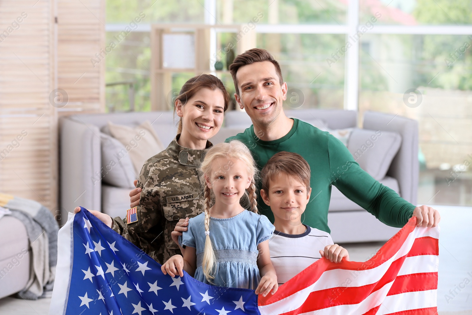 Photo of Woman in military uniform with her family holding American flag at home