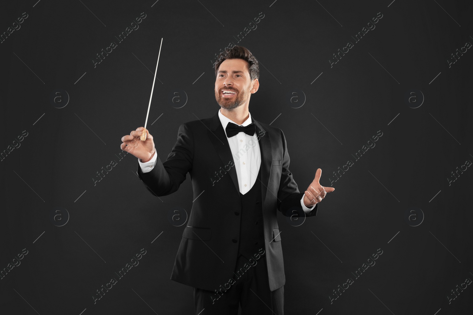 Photo of Happy professional conductor with baton on black background