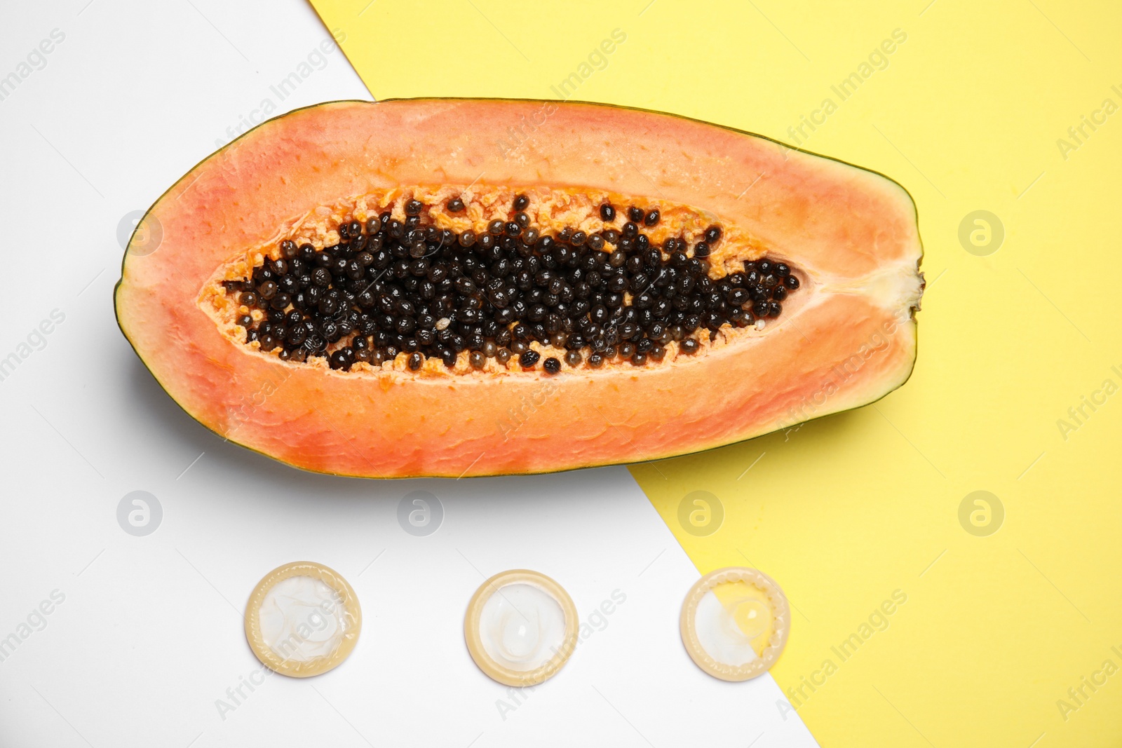 Photo of Flat lay composition with condoms and papaya on color background. Erotic concept