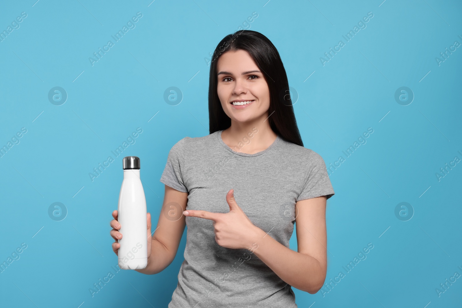 Photo of Young woman with thermo bottle on light blue background