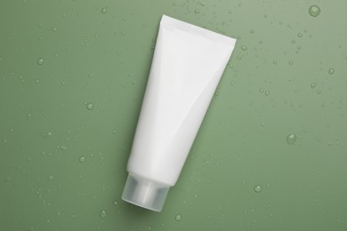 Tube of face cleansing product on green background, top view