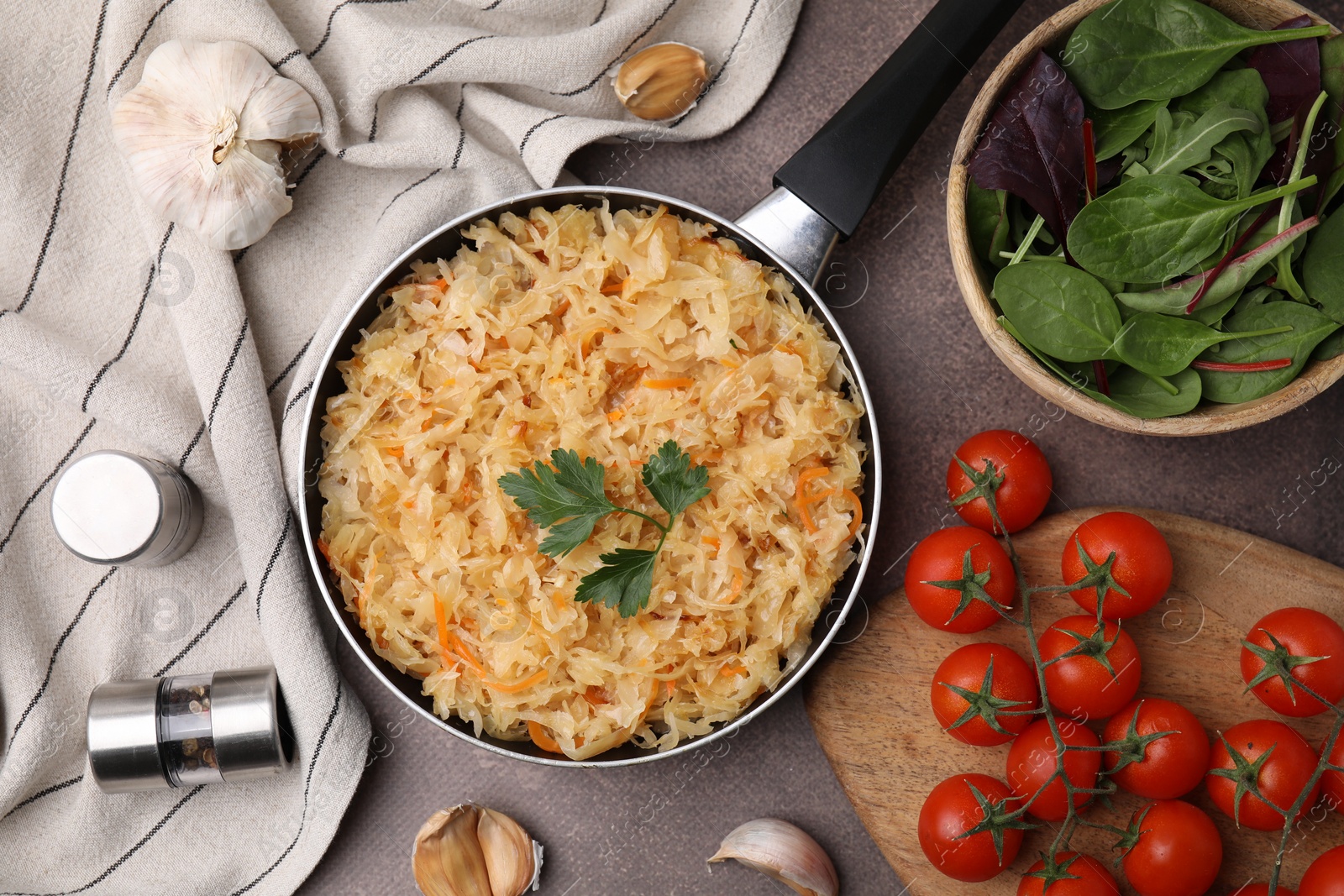 Photo of Frying pan with sauerkraut and products on brown table, flat lay