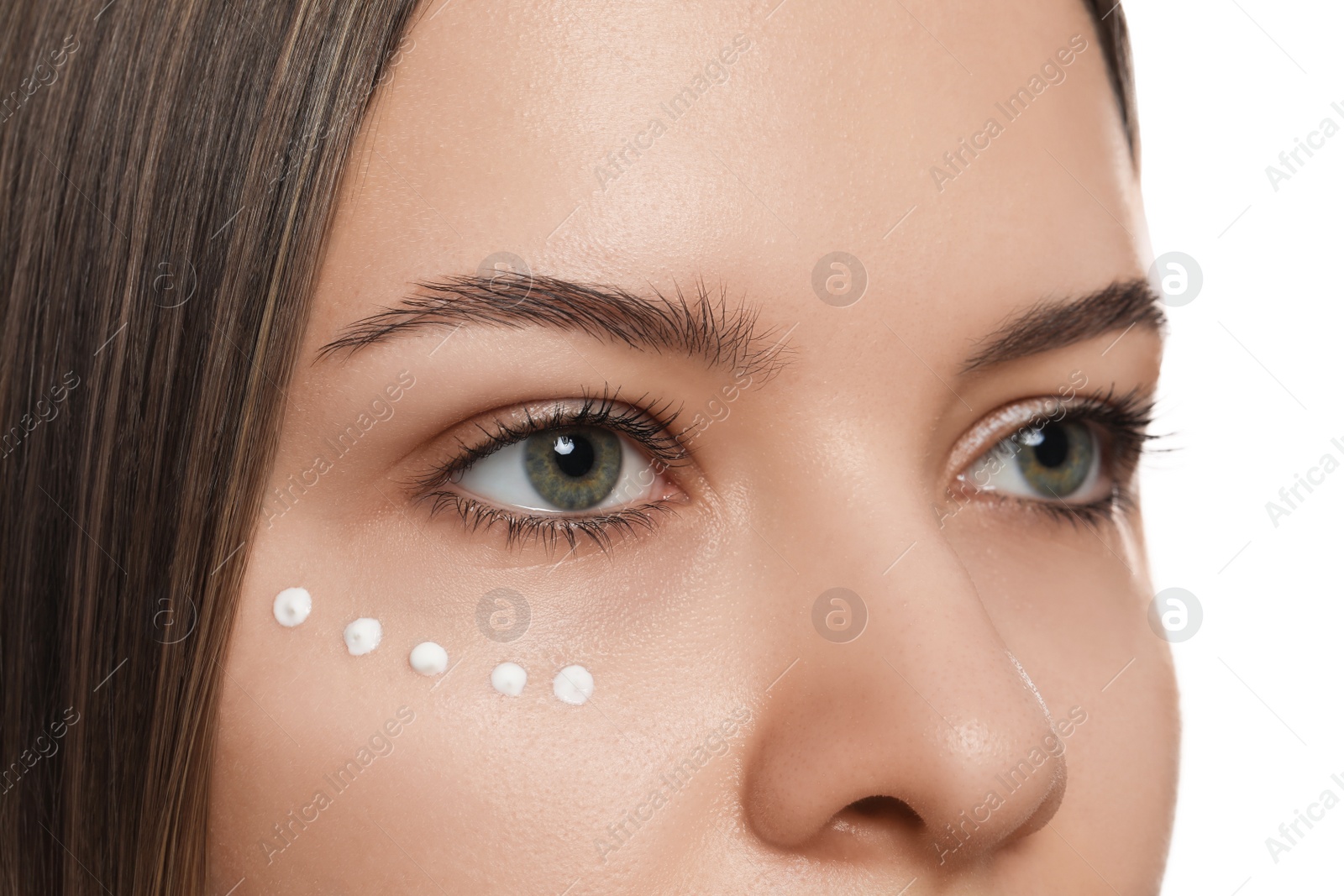 Photo of Young woman with cream around eye on white background, closeup