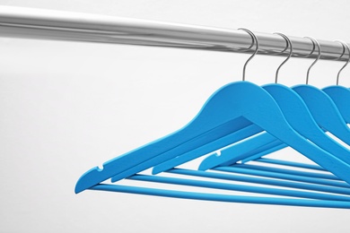 Photo of Clothes hangers on metal rail against light background