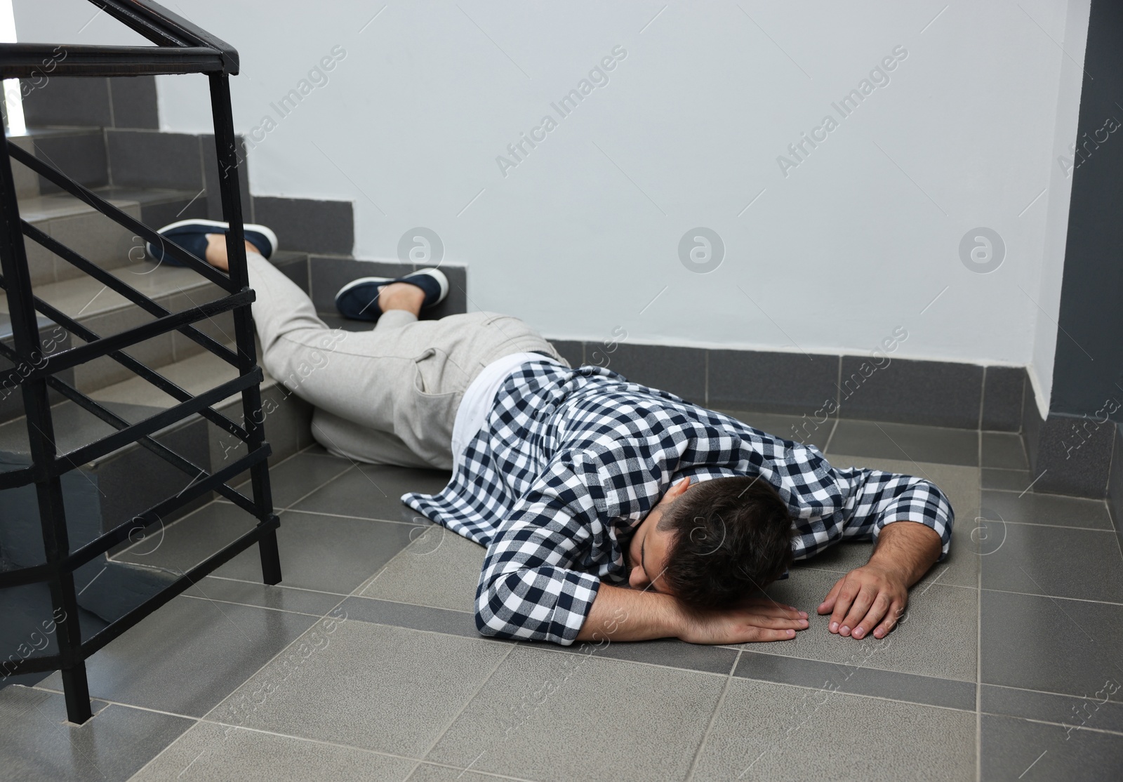 Photo of Unconscious man lying on floor after falling down stairs indoors