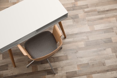 Stylish empty wooden table and armchair indoors, top view. Space for text