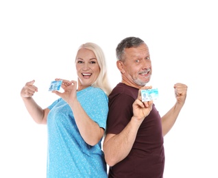 Happy mature couple with driving licenses on white background