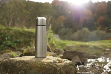 Photo of Metallic thermos on stone outdoors, space for text