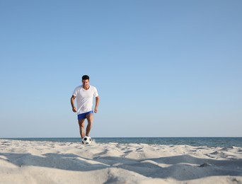 Photo of Man playing football on beach near sea