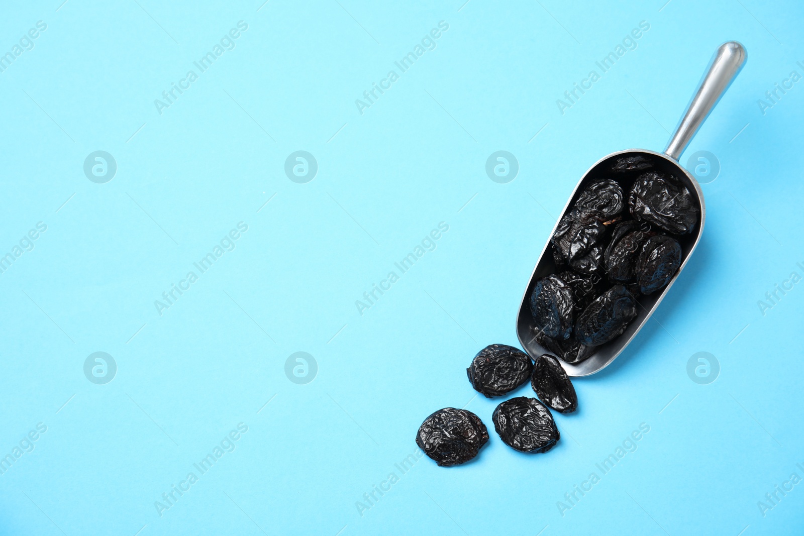 Photo of Scoop of dried plums on color background, top view with space for text. Healthy fruit