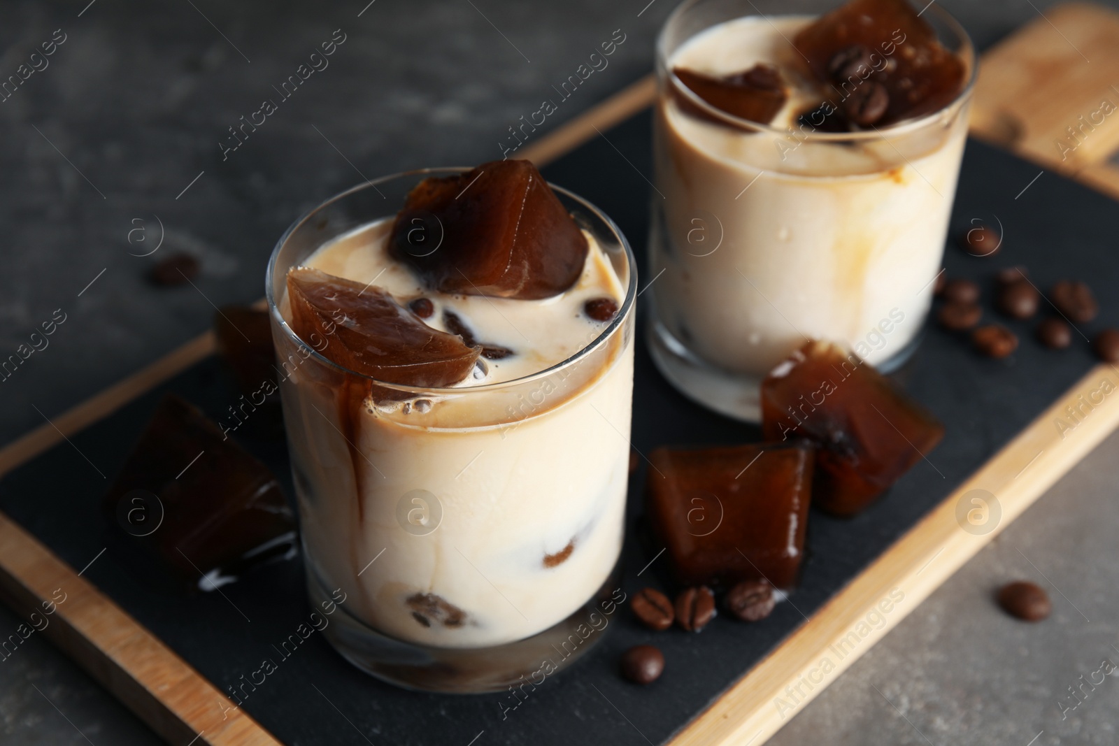 Photo of Glasses of milk with coffee ice cubes on grey table