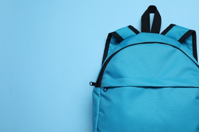 Photo of Stylish backpack on light blue background, top view. Space for text