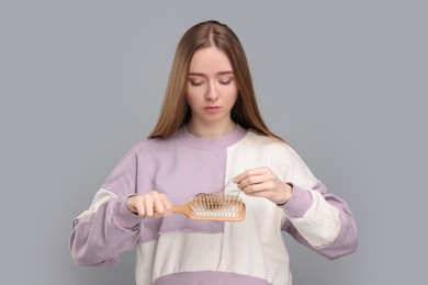 Photo of Woman holding brush with lost hair on light grey background. Alopecia problem