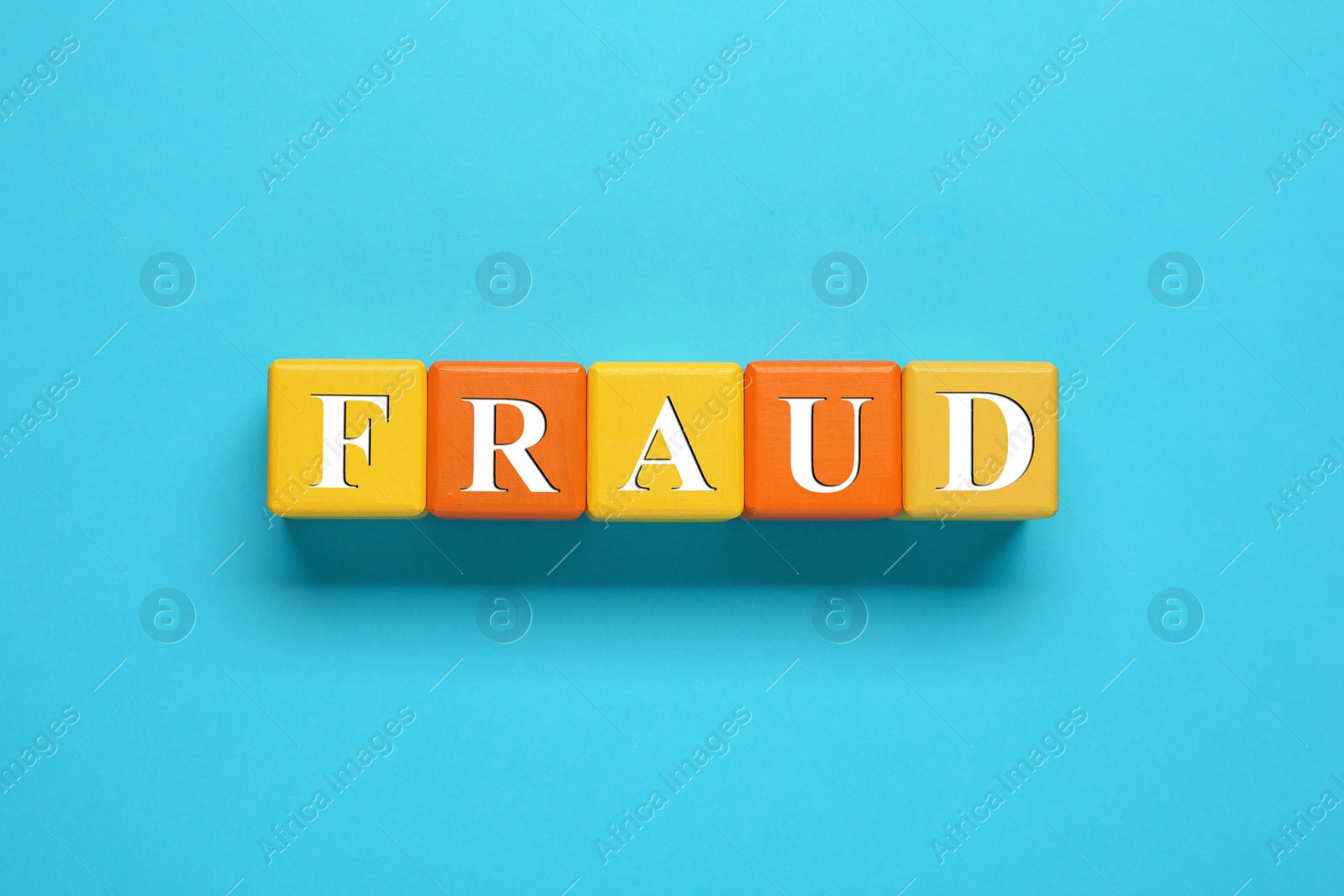 Photo of Word Fraud of wooden cubes with letters on light blue background, flat lay