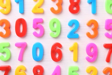 Colorful numbers on white wooden school desk, flat lay