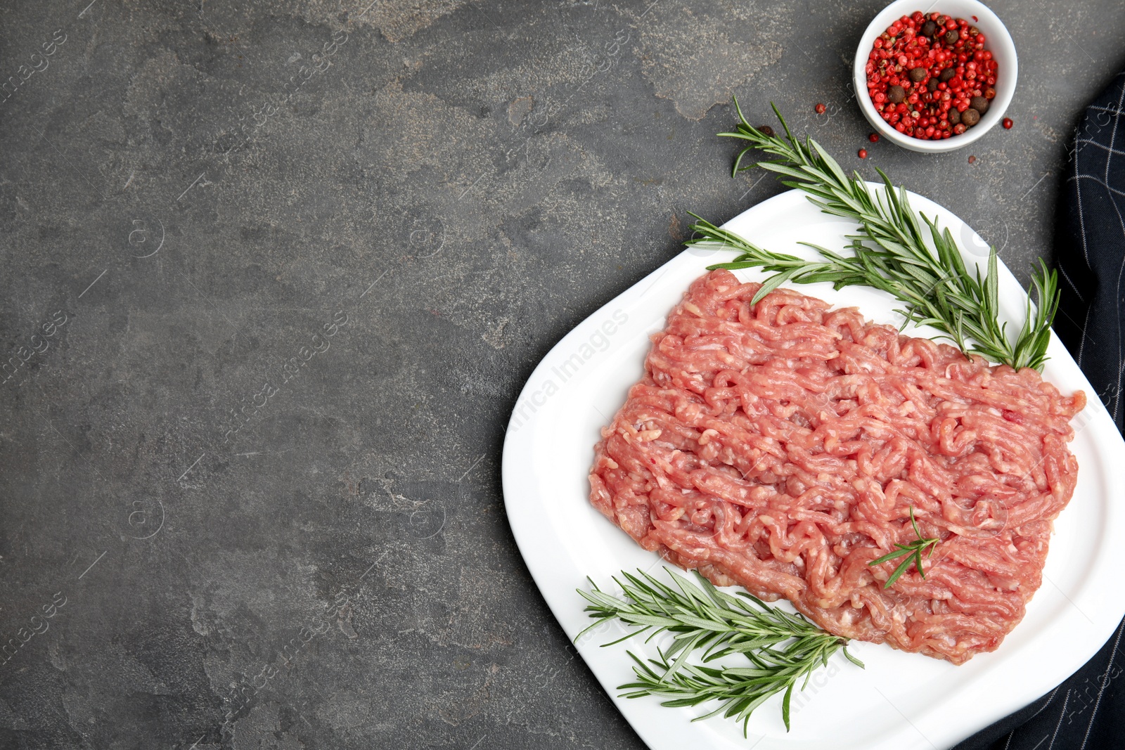 Photo of Raw chicken minced meat with rosemary and spices on grey table, flat lay. Space for text