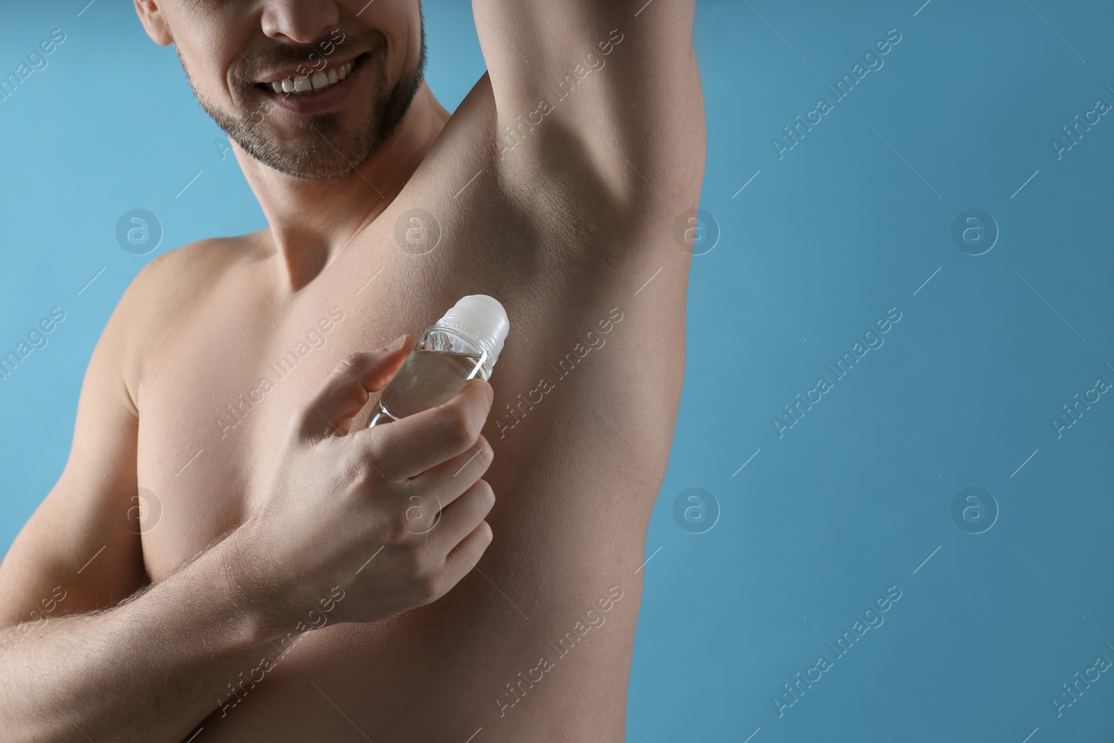 Photo of Man applying deodorant on turquoise background, closeup. Space for text