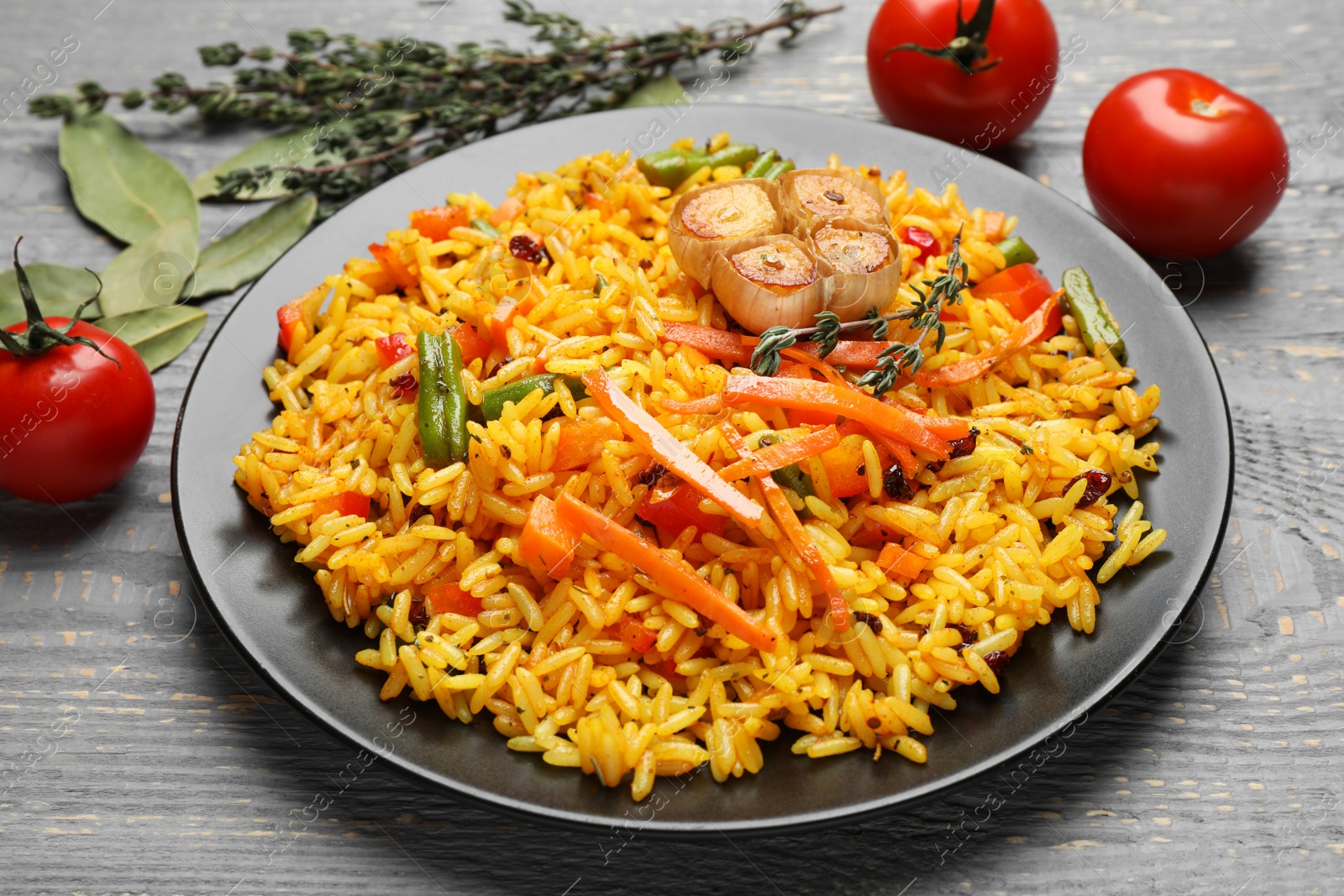 Photo of Tasty rice pilaf with vegetables on grey wooden table