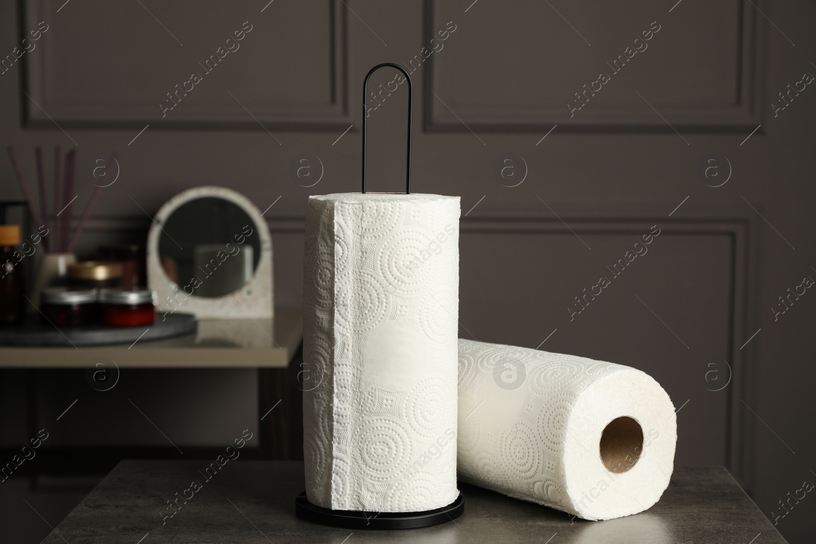 Photo of Holder with rolls of white paper towels on grey table