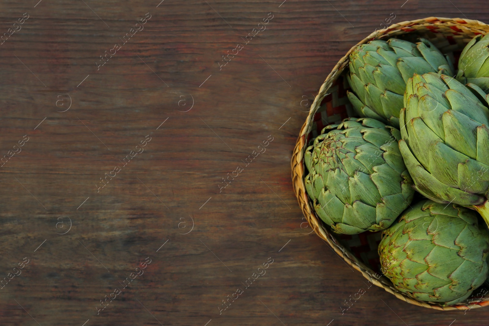 Photo of Tasty fresh raw artichokes on wooden table, top view. Space for text