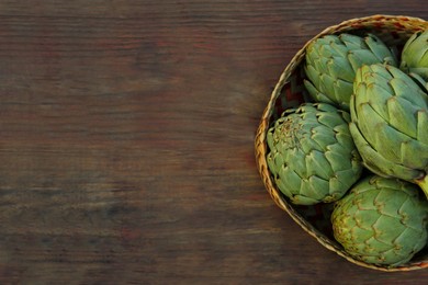 Tasty fresh raw artichokes on wooden table, top view. Space for text