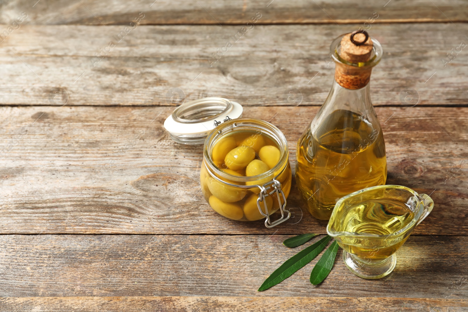 Photo of Beautiful composition with oil and ripe olives on wooden table