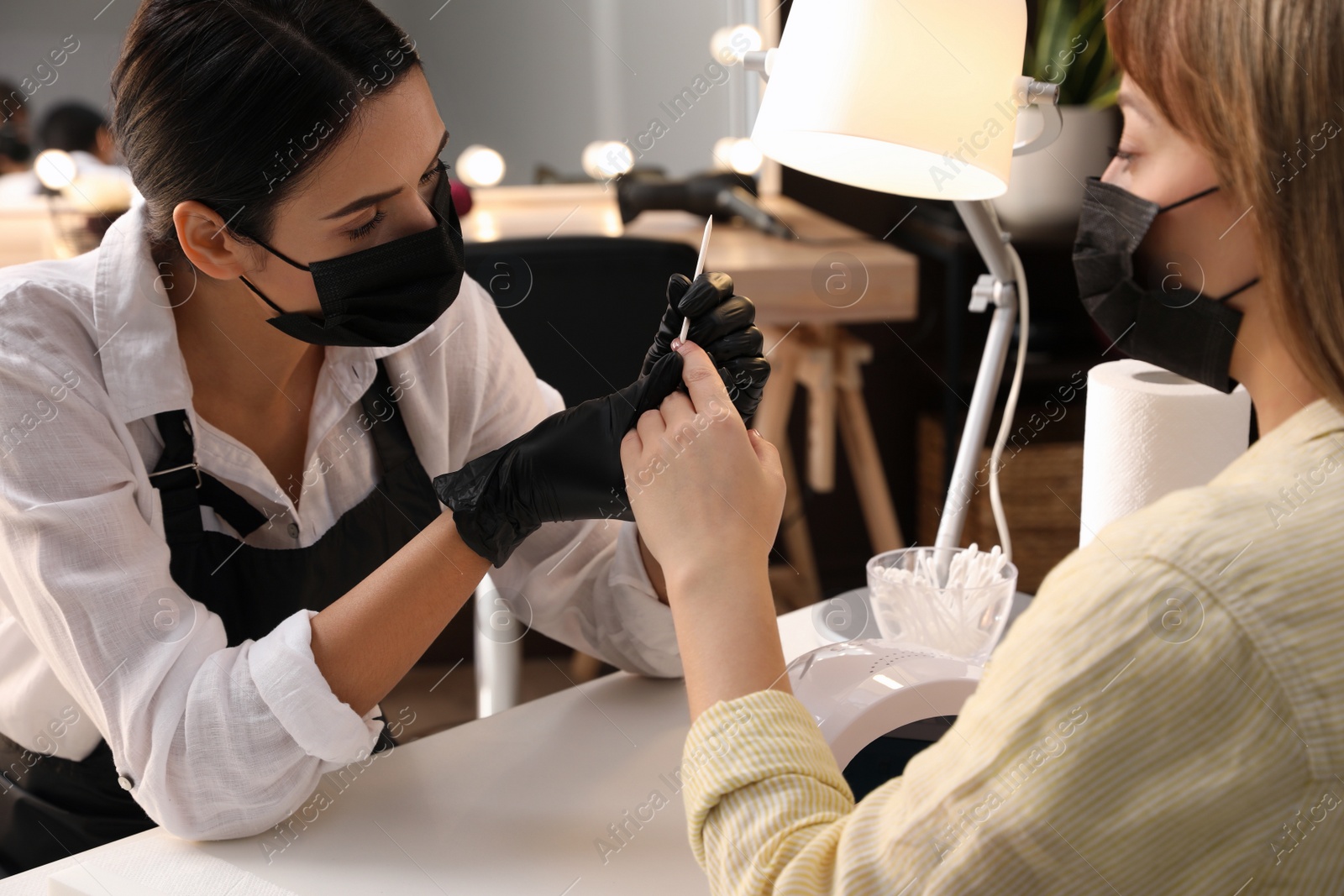 Photo of Professional manicurist working with client in salon. Beauty services during Coronavirus quarantine