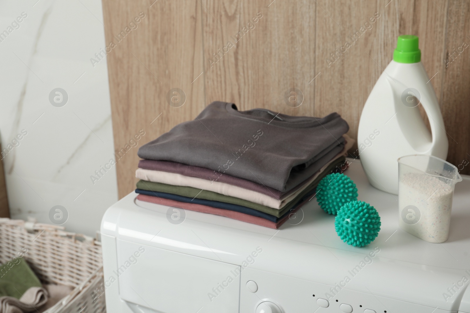 Photo of Dryer balls, stacked clean clothes and detergents on washing machine