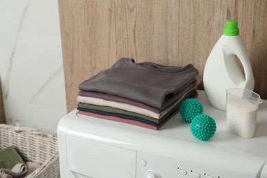 Dryer balls, stacked clean clothes and detergents on washing machine