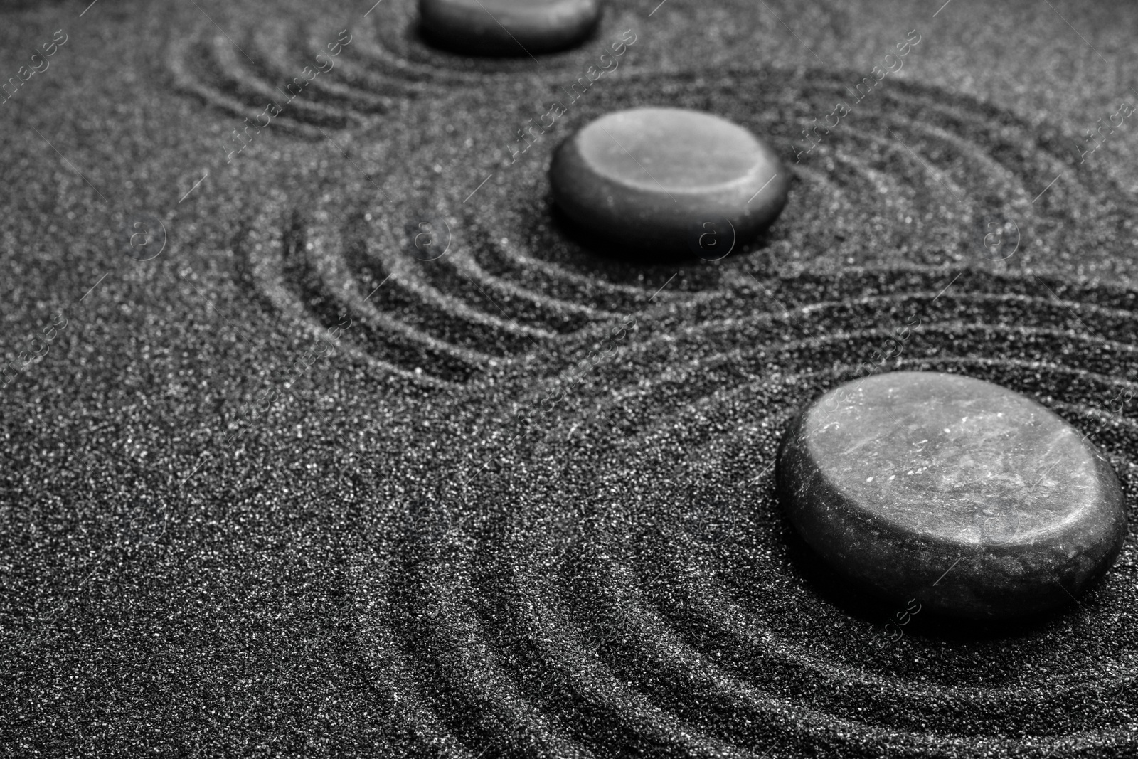 Photo of Black sand with stones and beautiful pattern. Zen concept