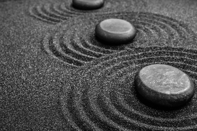 Photo of Black sand with stones and beautiful pattern. Zen concept