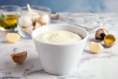 Photo of Composition with bowl of garlic sauce on marble table