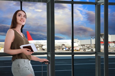 Image of Happy young woman with suitcase in airport