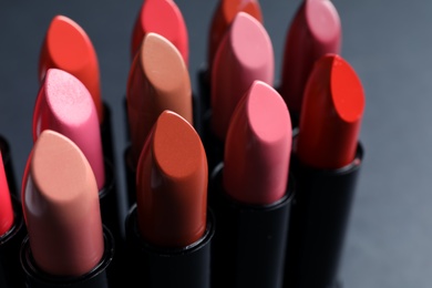 Photo of Set of different lipsticks on grey background, closeup. Cosmetic product